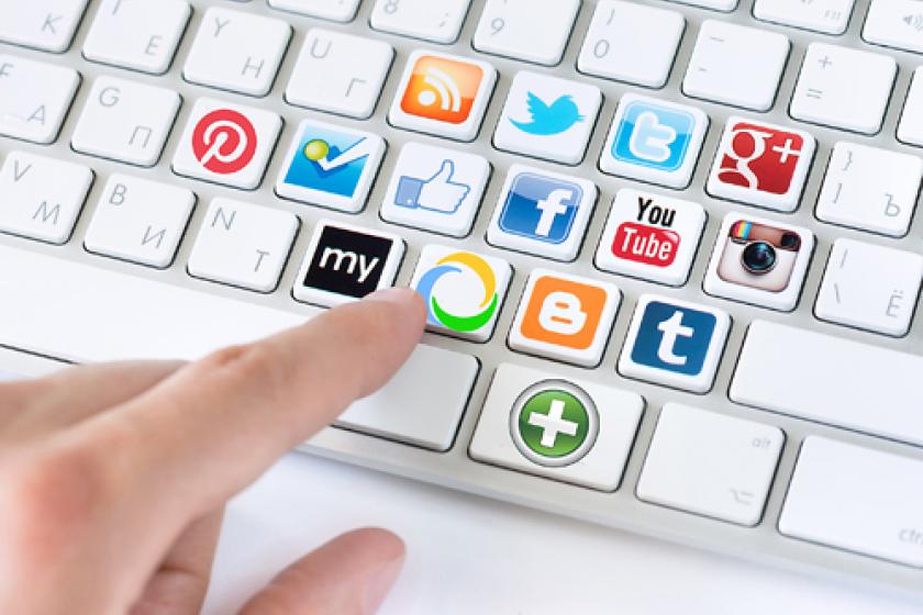 una mano usando un teclado con los logotipos de redes sociales